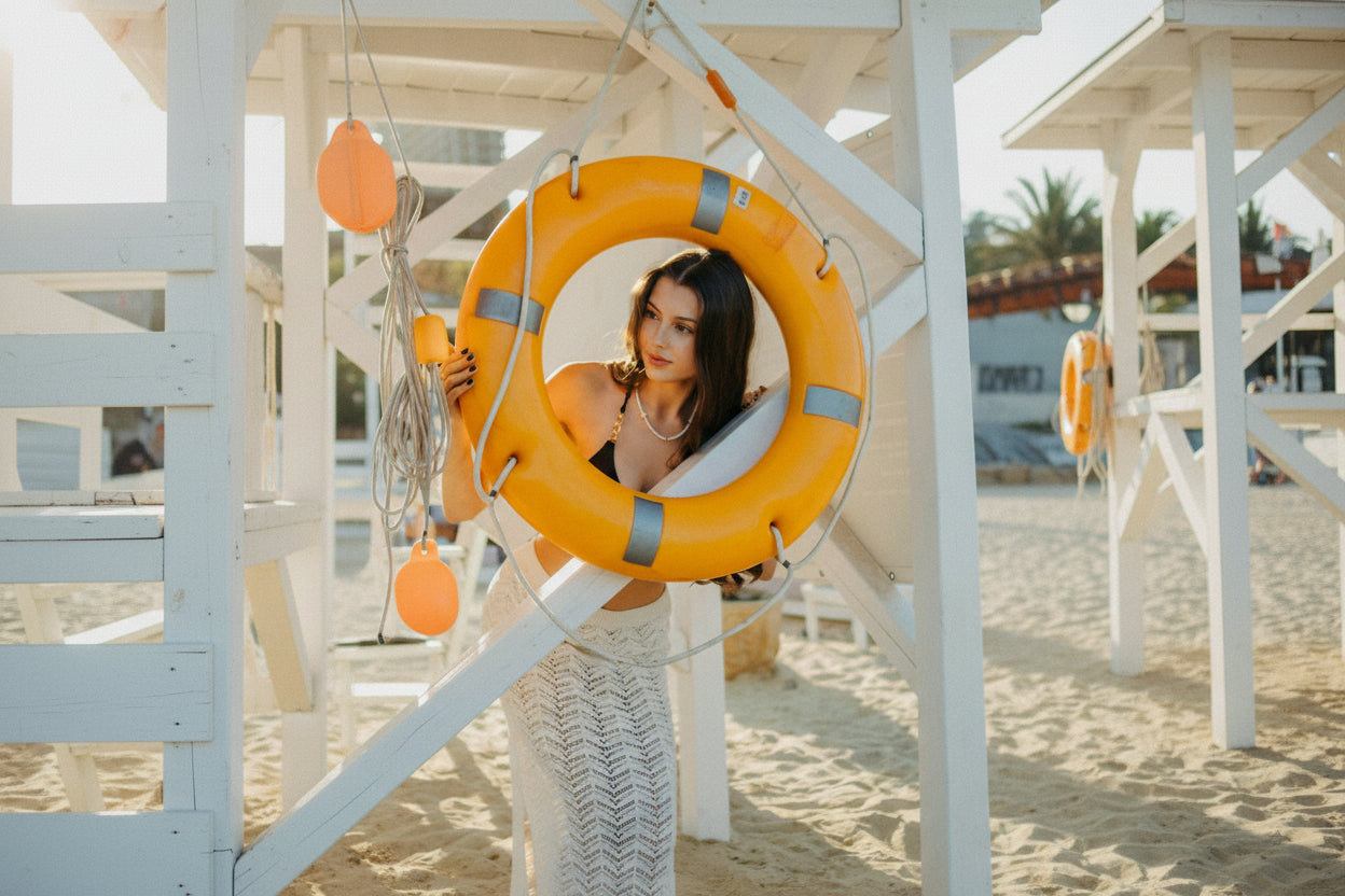 Woman standing behind an orange life buoy on a beach